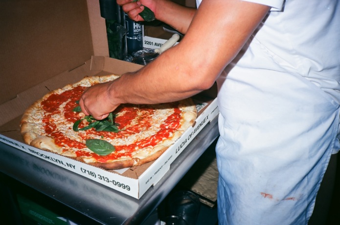 Putting the final touches on a pizza at Lucia Pizza.