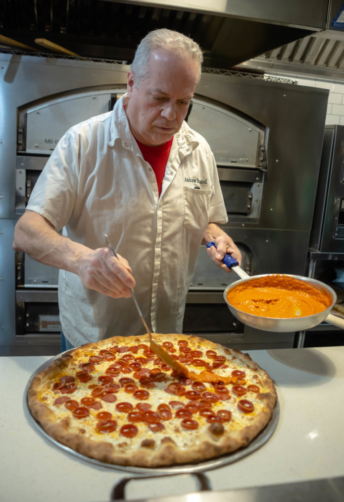 Andrew Bellucci adds sauce to one of his pizzas at Bellucci's Pizzeria in Astoria.