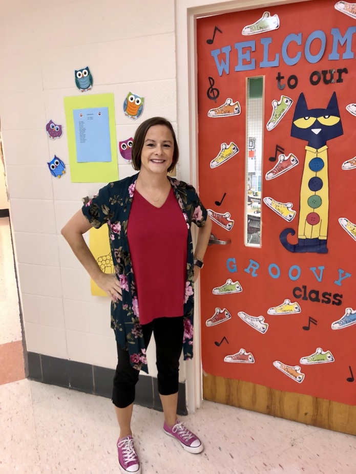 Rachel Wilson stands outside the colorful door of her kindergarten classroom