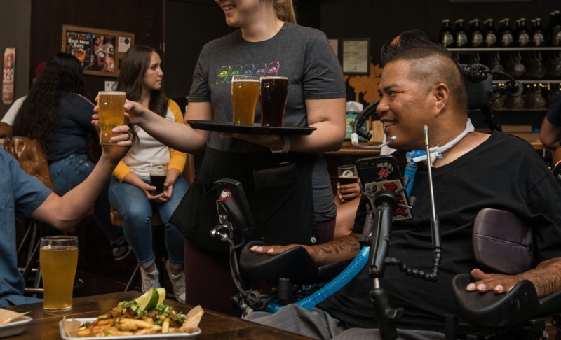 man in wheelchair sitting in a restaurant smiling