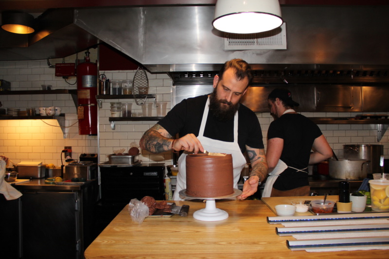 Joshua Pinsky, chef of Claud, icing the restaurant's famed chocolate cake.