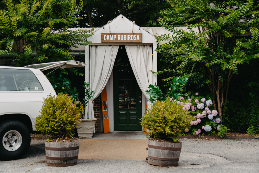 Camp entrance with a wooden sign that reads "Camp Rubirosa"