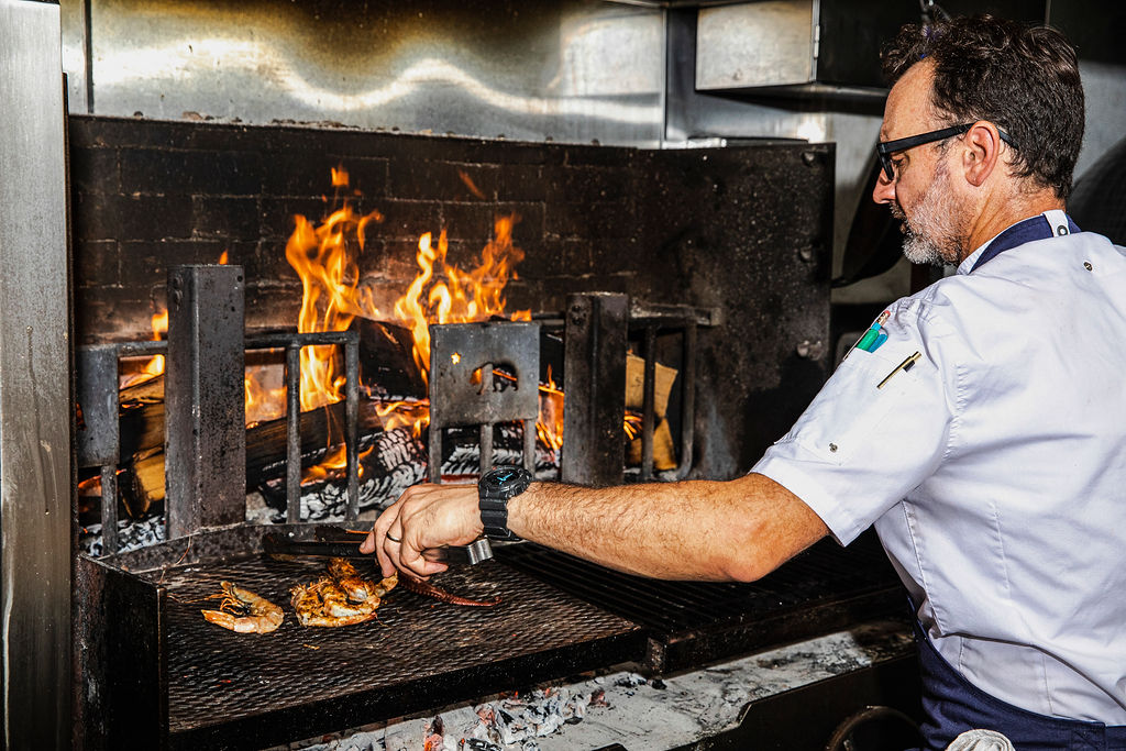 chef cooking shrimp on open flame in kitchen