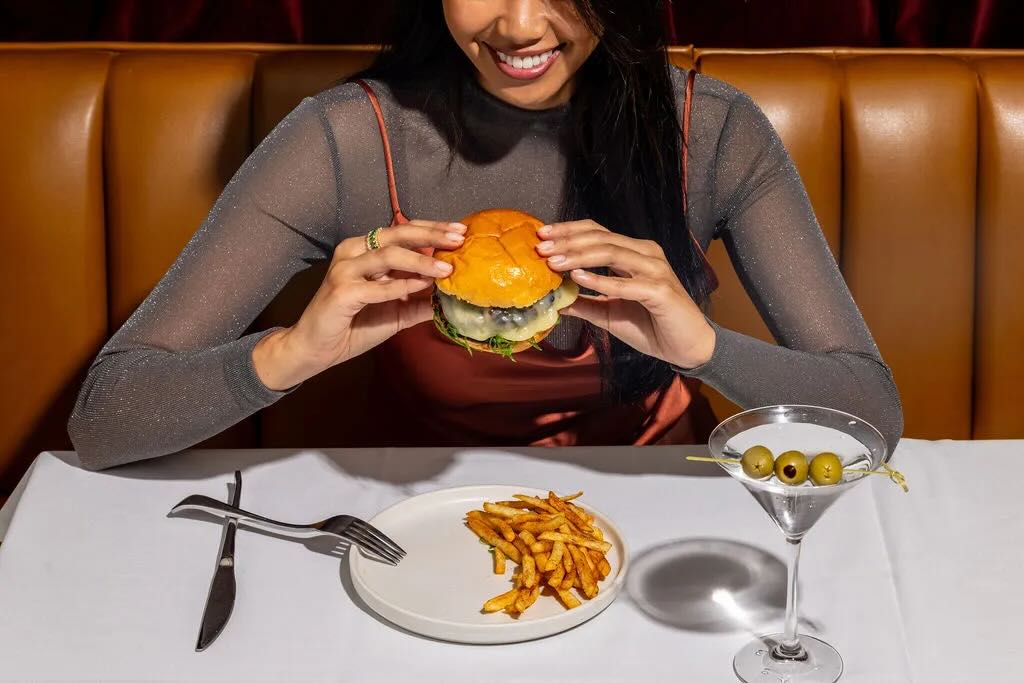 girl at table eating a hamburger