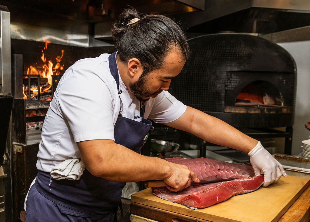 man filleting fish in kitchen