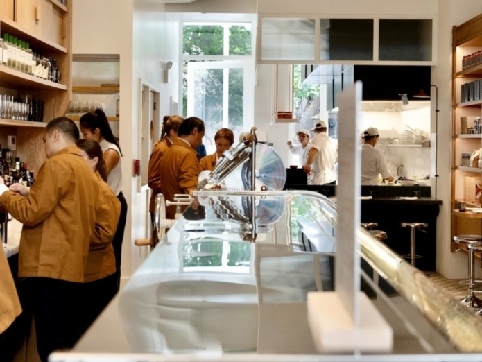 Staff members of Misipasta are actively working in a light-filled white and wood restaurant