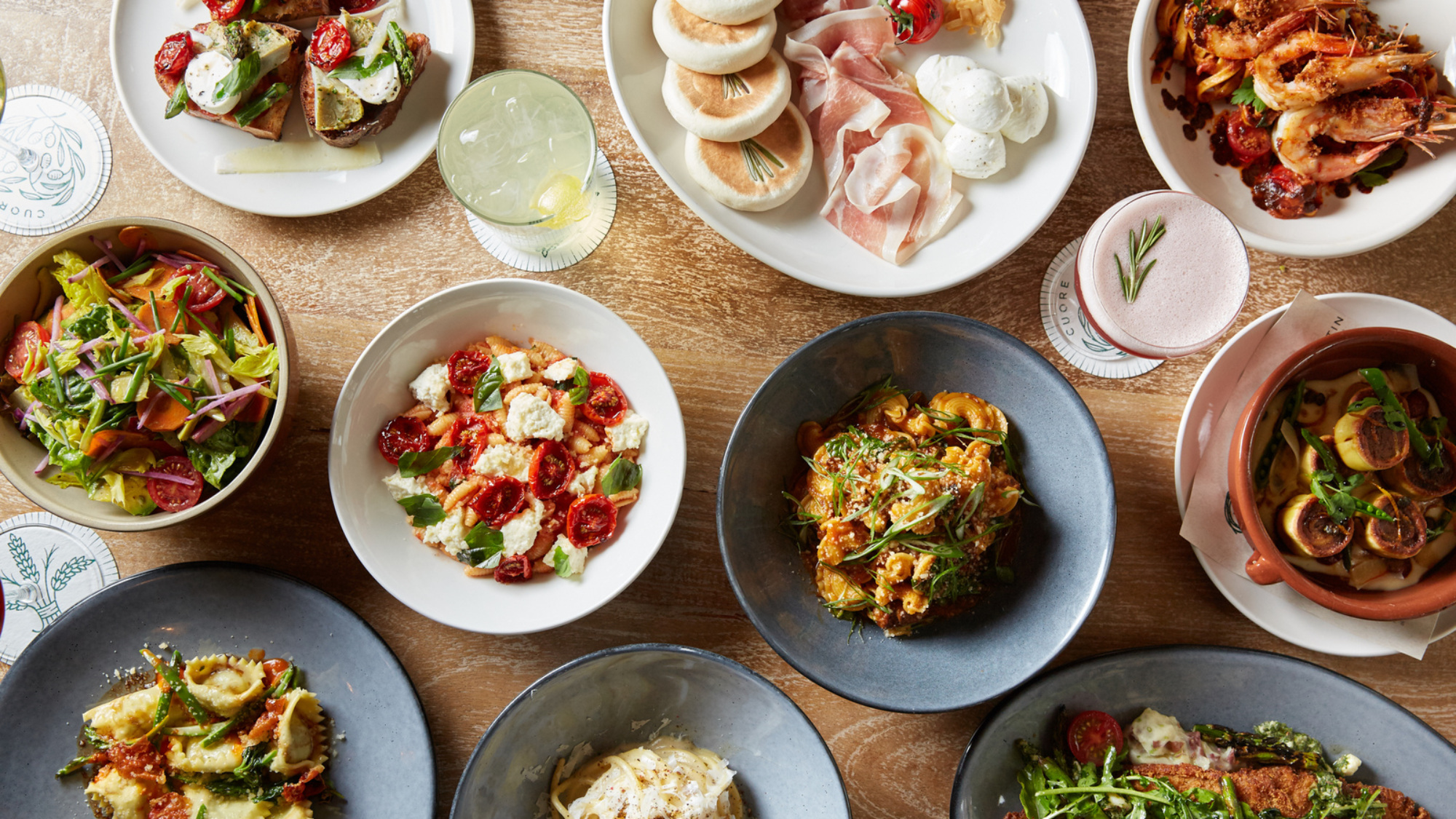 table top full of small plates of pastas, salad, and bruschetta