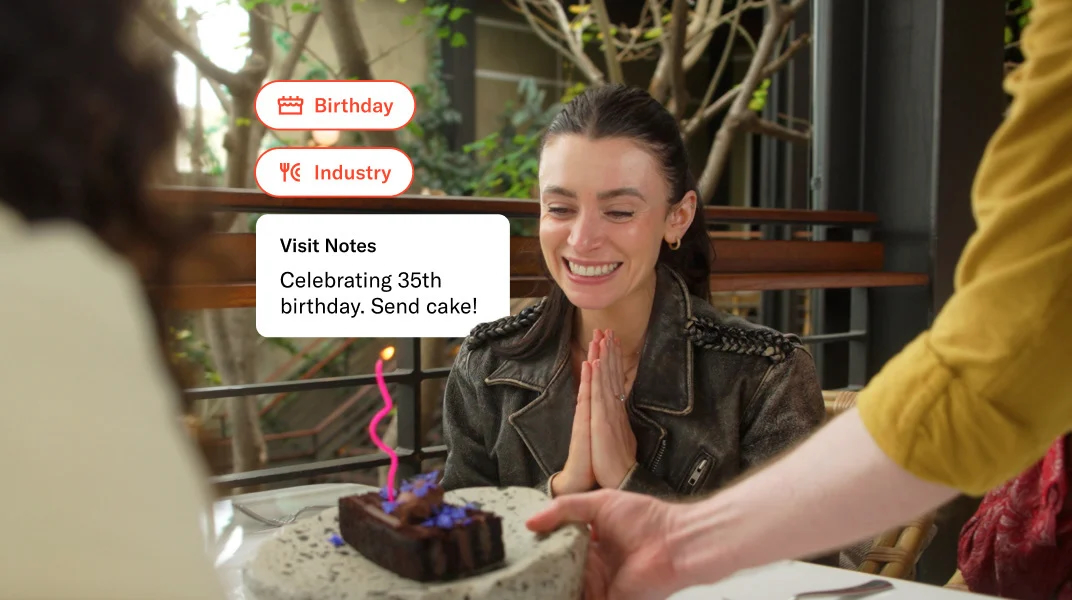 Smiling woman looks at a cake with a candle in it