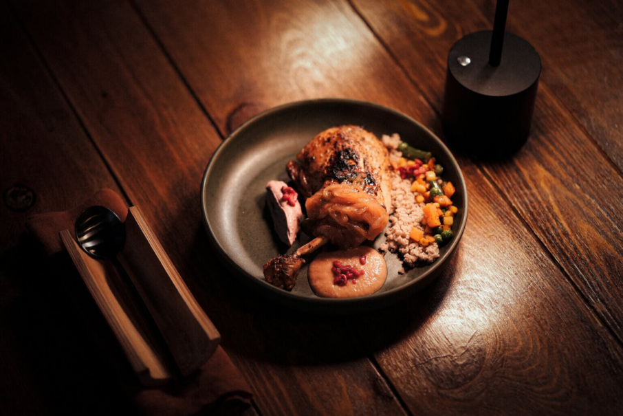Senegalese chicken, caramelized onion, & coconut forio pilaf sit on a dark gray plate on a wooden table