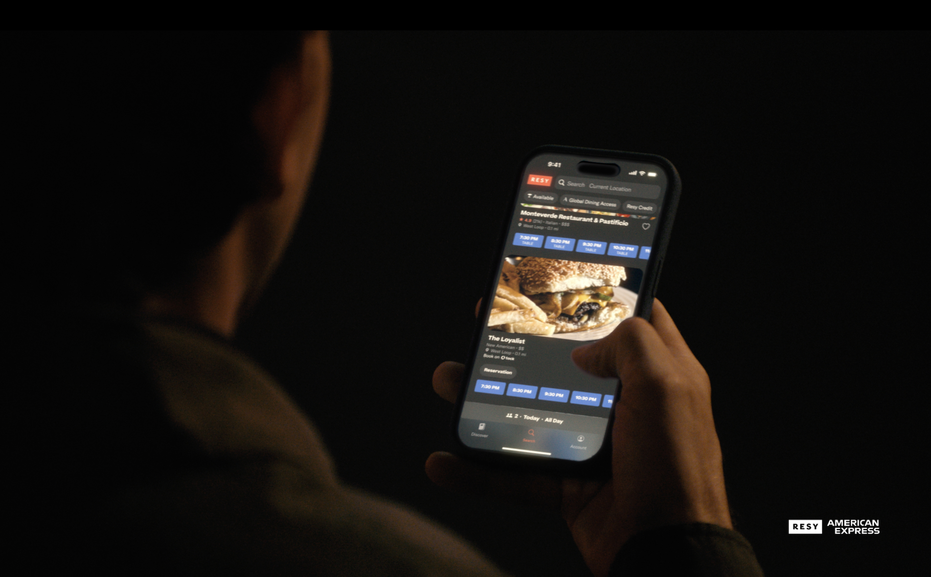 A man scrolls through reservation options on the Resy app on a mobile phone